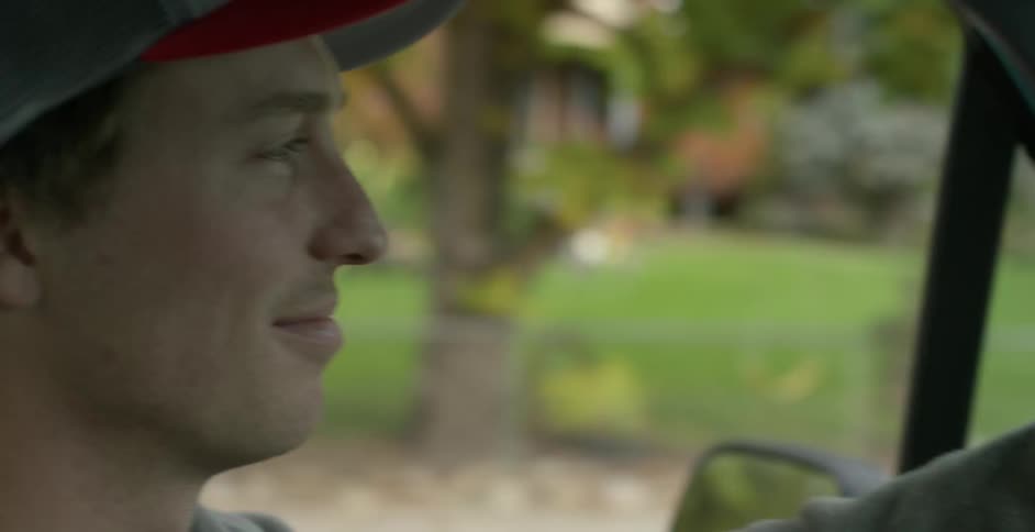 A white man drives down a street and looks at the houses going by