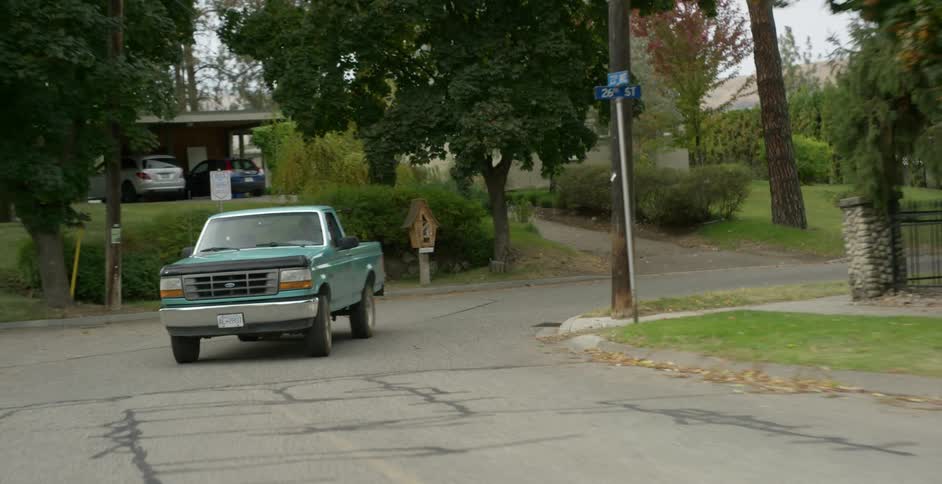 A man drives a truck through a neighborhood