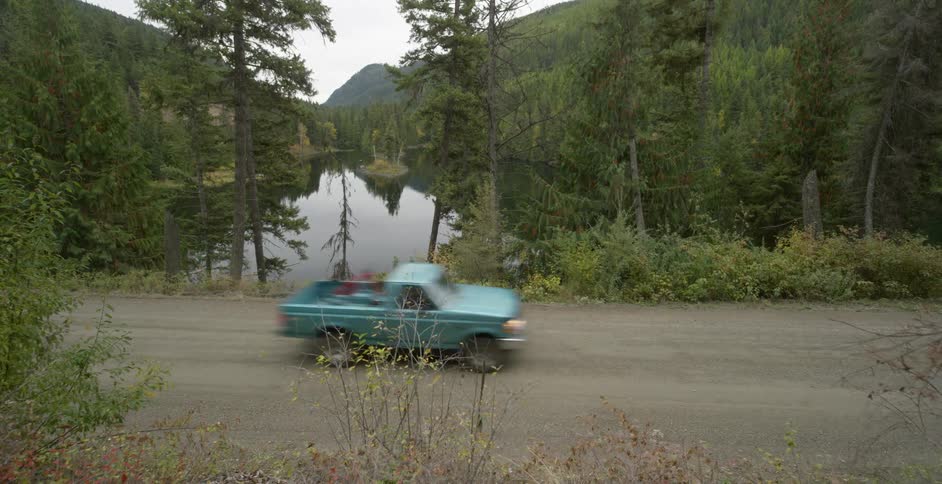 A truck drives past a lake