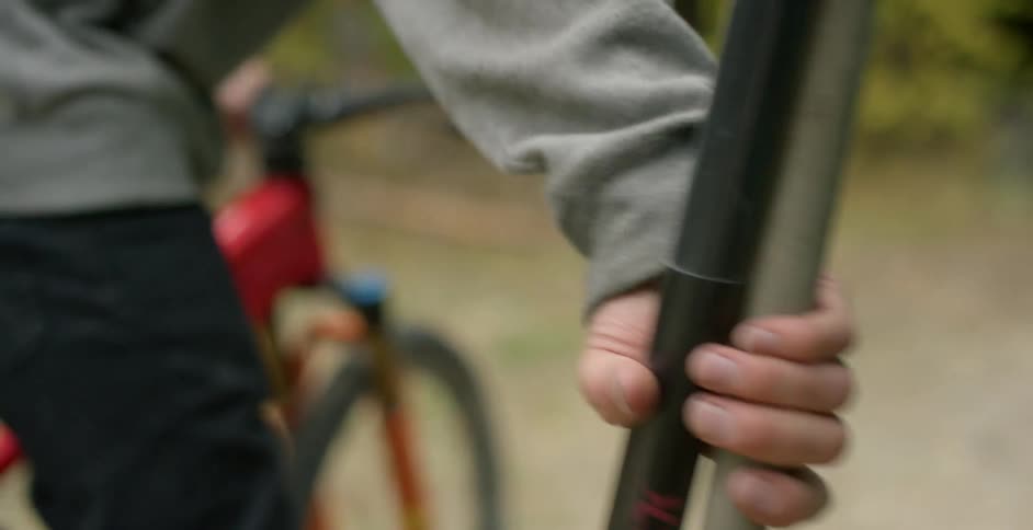 A white male with a bicycle grabs some tools and walks to the woods