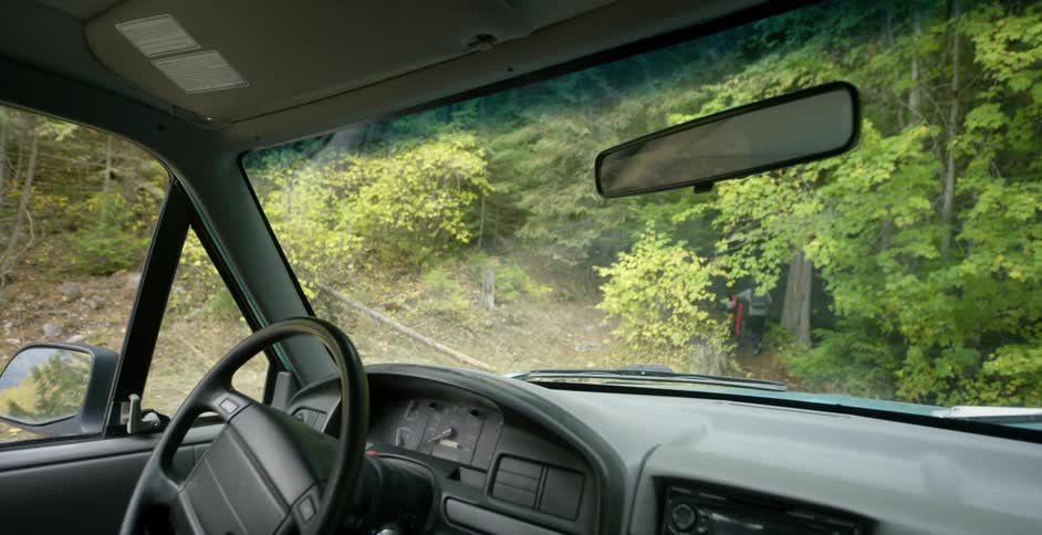 A person pushes a bike into a heavily wooded area