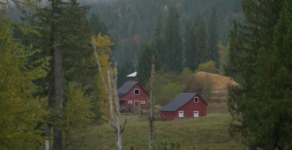 A truck travels a road beside a farm house and barn