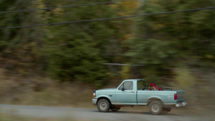 A person drives a truck with a bicycle in the back