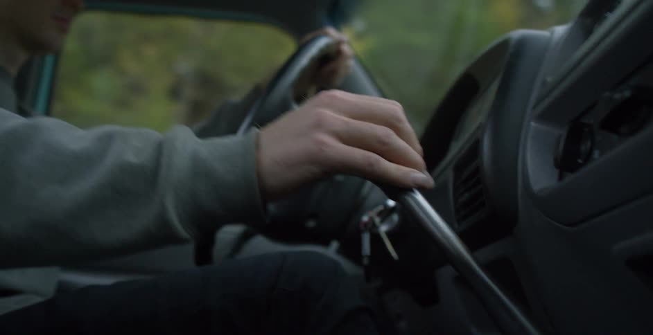 Young man shift gears while driving a manual car through a rural road