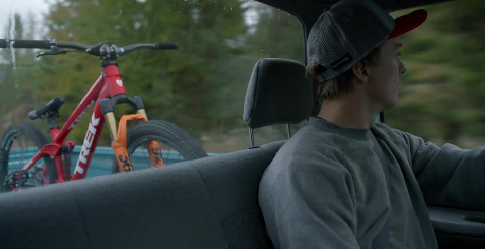 A man drives through a rural area with a dirt bike in the back of his truck