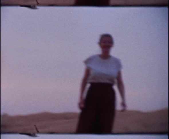 A woman walks in a desert and runs towards the camera