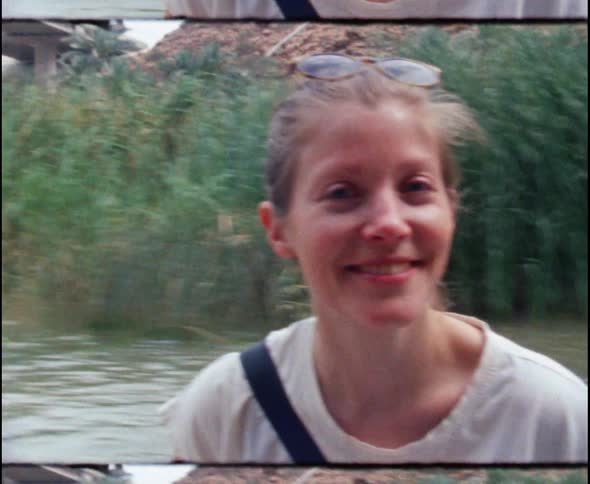 A white woman travels on a boat on the river that heads for a bridge