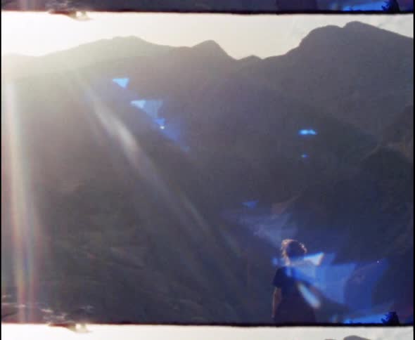 A woman stands on a cliff and looks at the mountains
