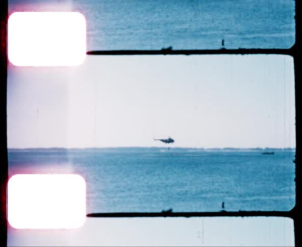 Navy helicopter hovers over the ocean near a boat