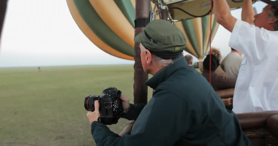 A man in a hot air balloon holds a camera