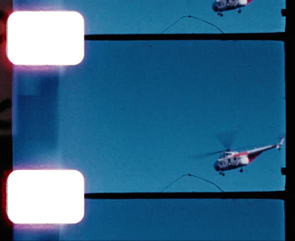 A helicopter flies across a blue sky