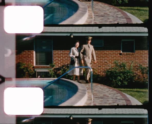 A military officer walks around a pool with an older white woman
