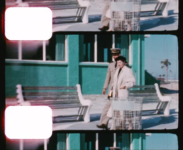 Man in uniform walks with a woman near a building on the beach