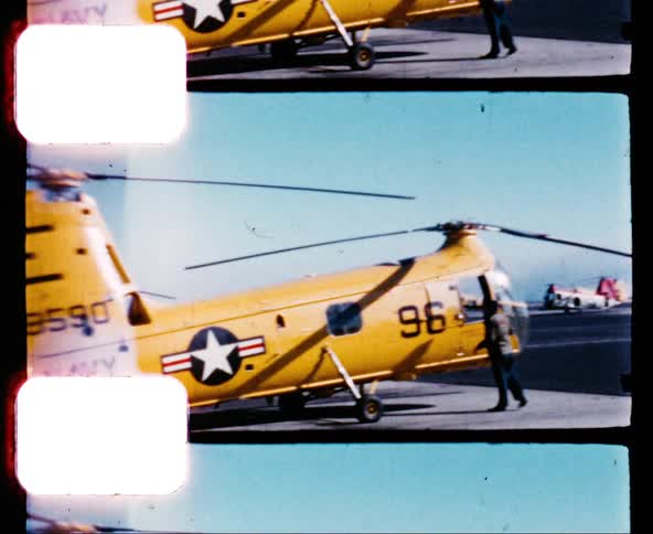 A navy helicopter sits on the tarmac at an air base