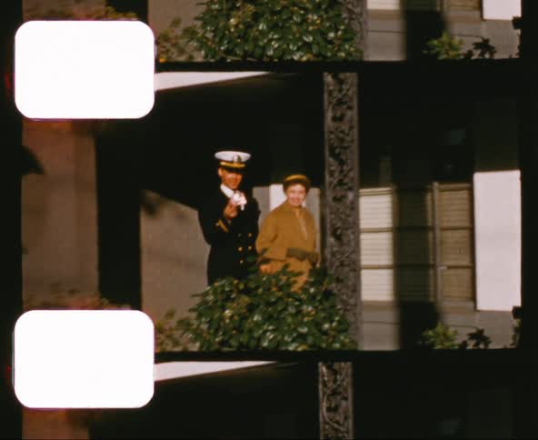 A mother and her military officer son walk out of a building and across a porch