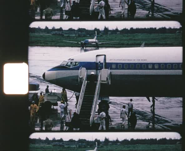 Airplane parked in airport runway with crew walking around