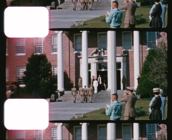 Military officers march to the entrance of a building and then stand at attention