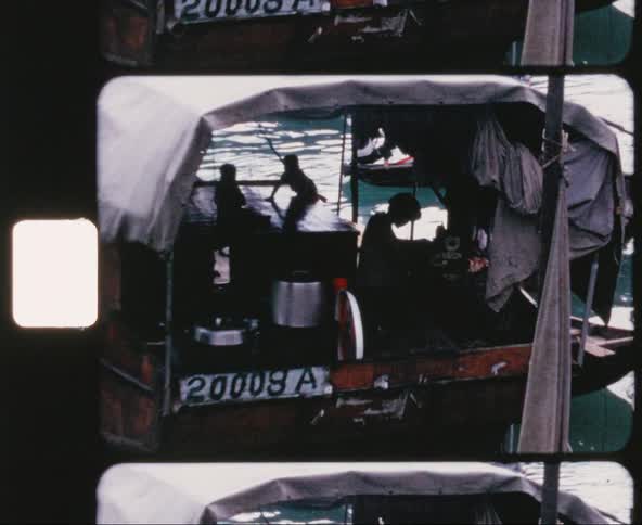 A boat with an adult and two children floats in a crowded area of water
