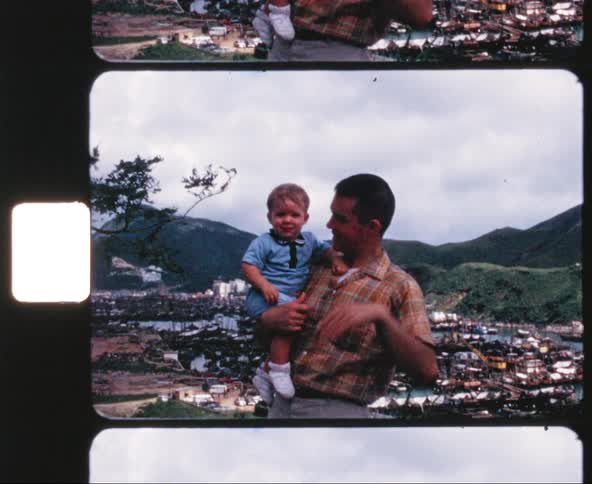 Father holding his son poses for the camera on a city background