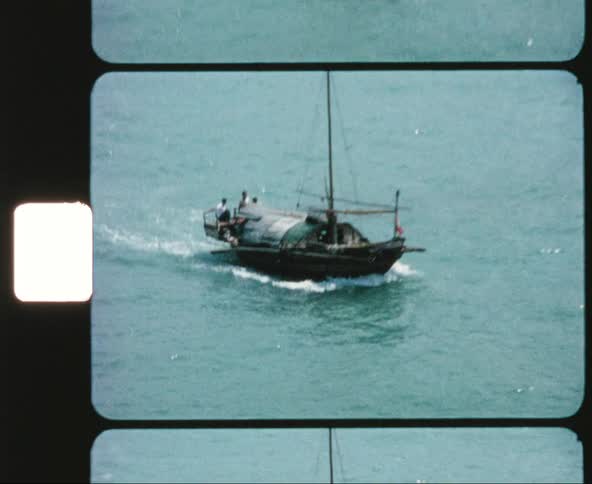 Boats travel in the ocean water as buildings sit on the nearby shore