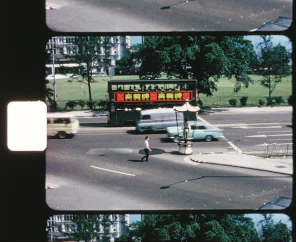 A man quickly crossing a road while traffic travels along a nearby street