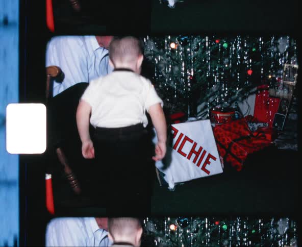 Father and son unwrapping christmas gift next to christmas tree
