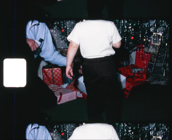Father pointing at christmas gift under the tree to his son