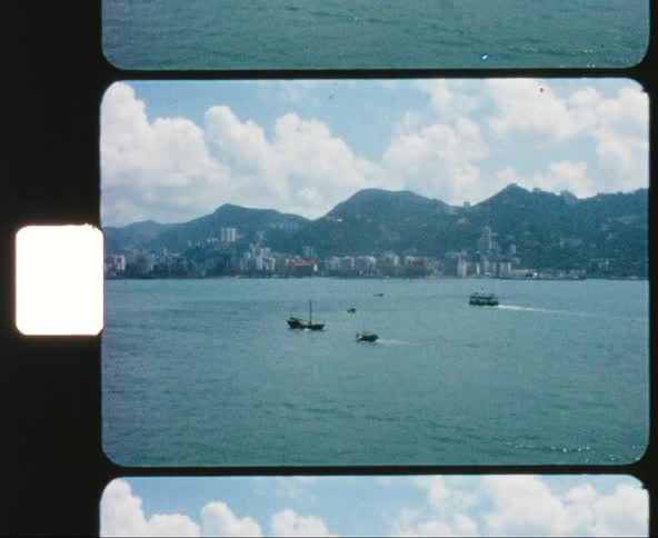 Boats and ships travel across the sea with a coastal city in the background