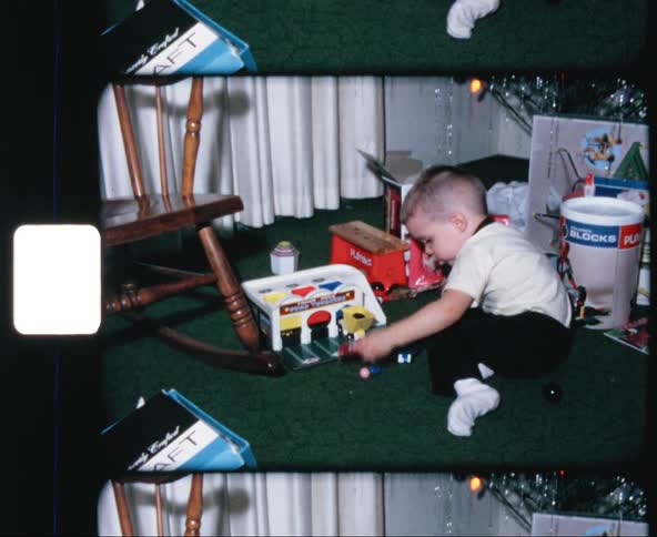Vintage film of a boy playing with toys under a christmas tree