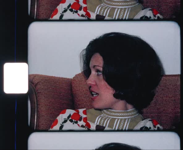 Film footage of a woman sitting on a couch talking