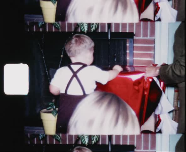 A male toddler and an adult unwrap a large gift