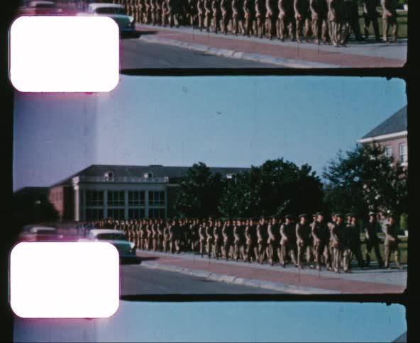 Military personnel march down the sidewalk on a military base