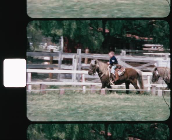 A young boy riding a pony by himself around a corral