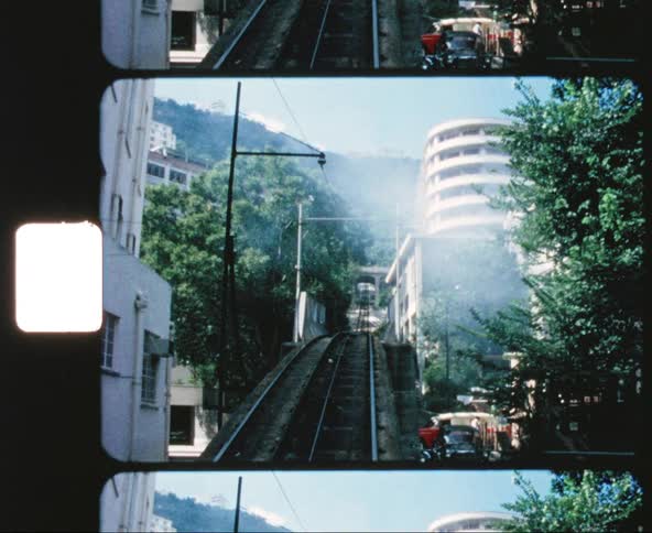 A train moves over elevated tracks in a city neighborhood and downtown area