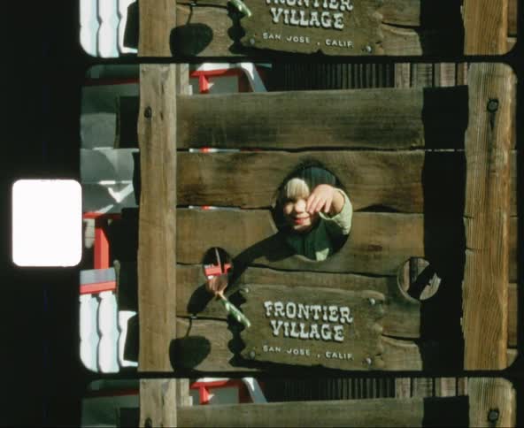 A little boy puts his hands and head through a wooden stock at an amusement park