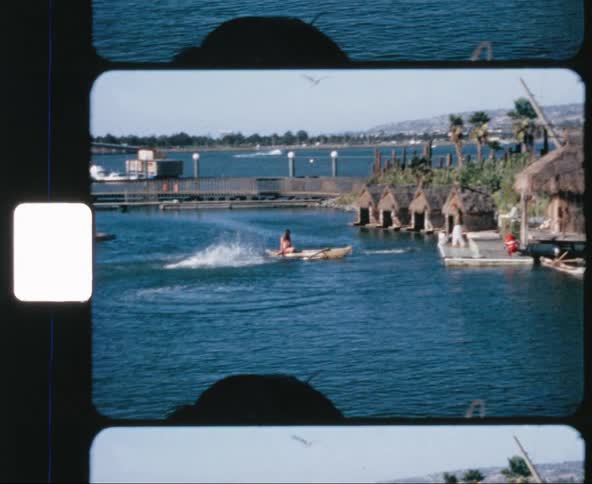 Dolphin jumps in the water near a canoe that is approaching the dock