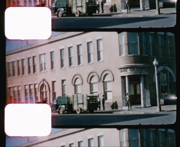 People stand near green truck with trailer near street corner in front of bank