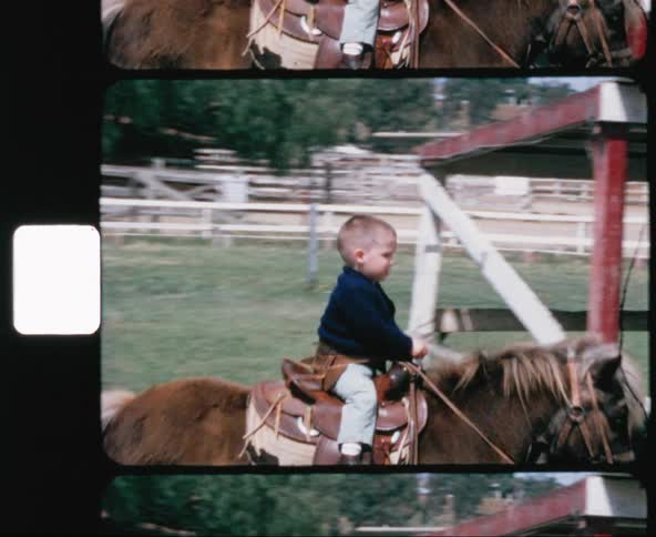 A small boy rides a pony in a paddock