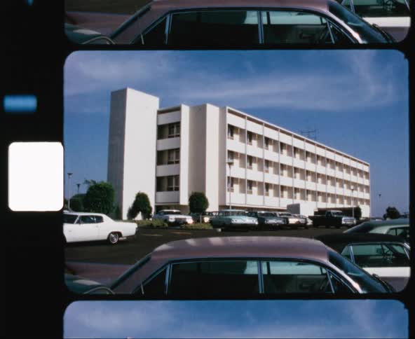 A parking lot at an office building full of older cars