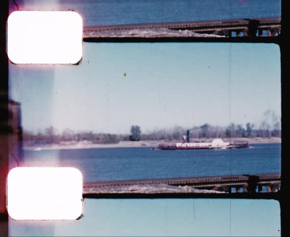 A large steamboat spewing black smoke into the air as it travels down a river