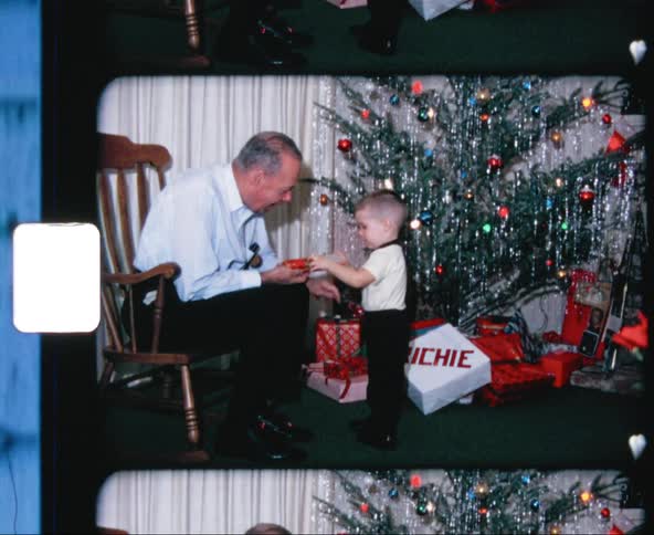 Grandfather sitting on rocking chair playing with grandson near christmas tree