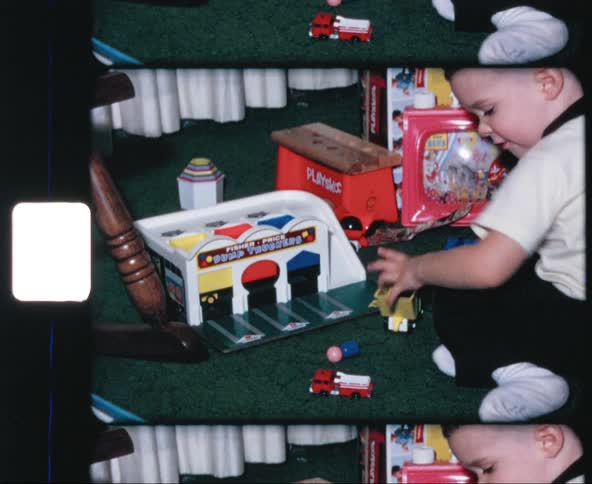 A young white boy plays with toy trucks and cars and play sets