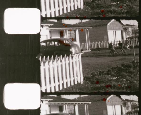 Children playing in front yard of home near white picket fences in the sixties