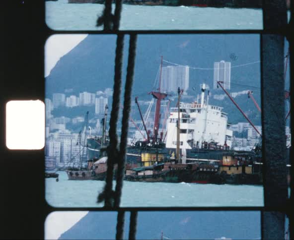 A pair of ships traveling side by side off the coast of a city