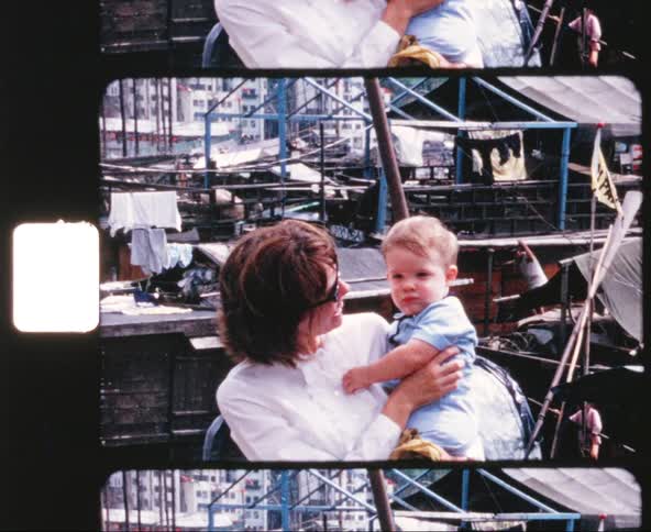 Mother holds her baby and poses for the camera at a port town