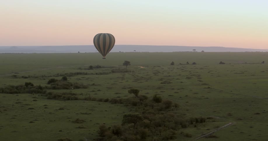 A hot air balloon floats over a rural area