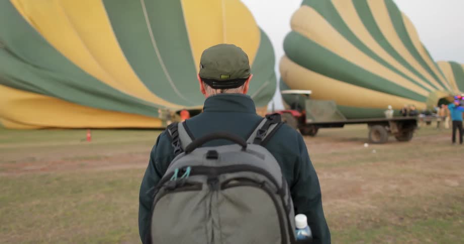 A man walking towards hot air balloons as they fill