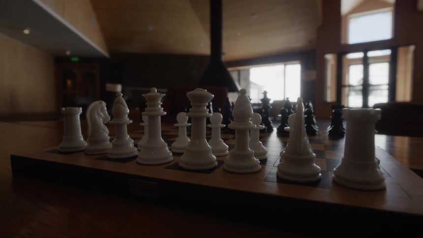 A wooden chess board is set up in a living room