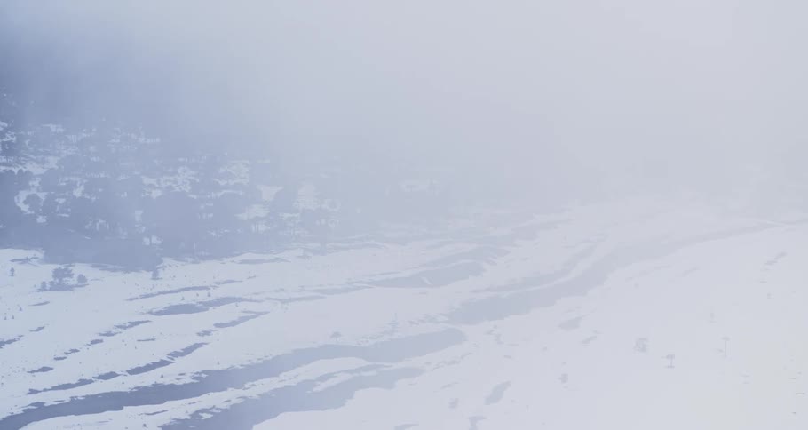 Aerial pushing through fog over a snowy forest