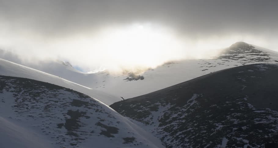 Aerial push towards the sun in snowy mountains
